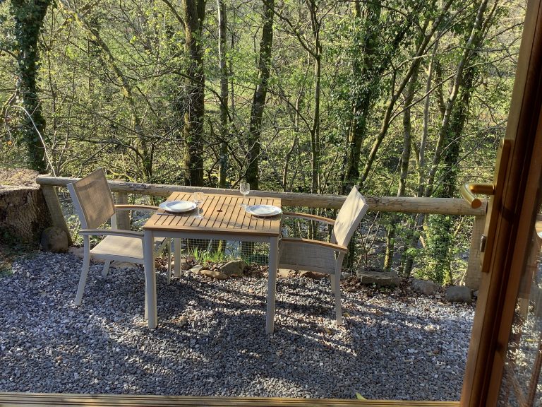 Two chairs and a table over looking a bank of the river tawe.